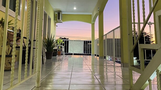A covered outdoor area with a tiled floor, potted plants, and a staircase leading to an upper level. - Hotel Posada Los Olivos Los Mochis (Los Mochis)