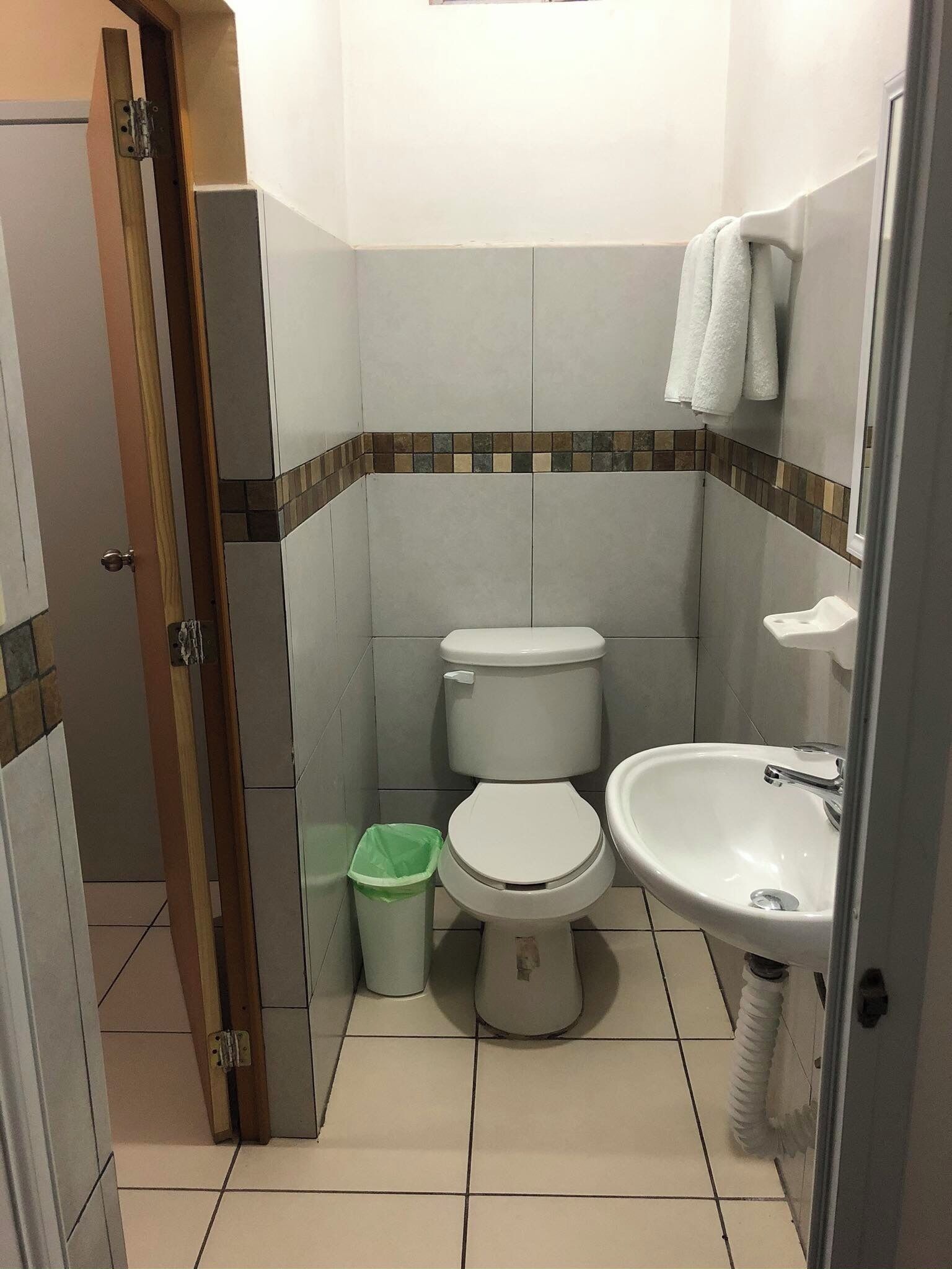Ein kleines Badezimmer mit Toilette, Waschbecken und Mülleimer.