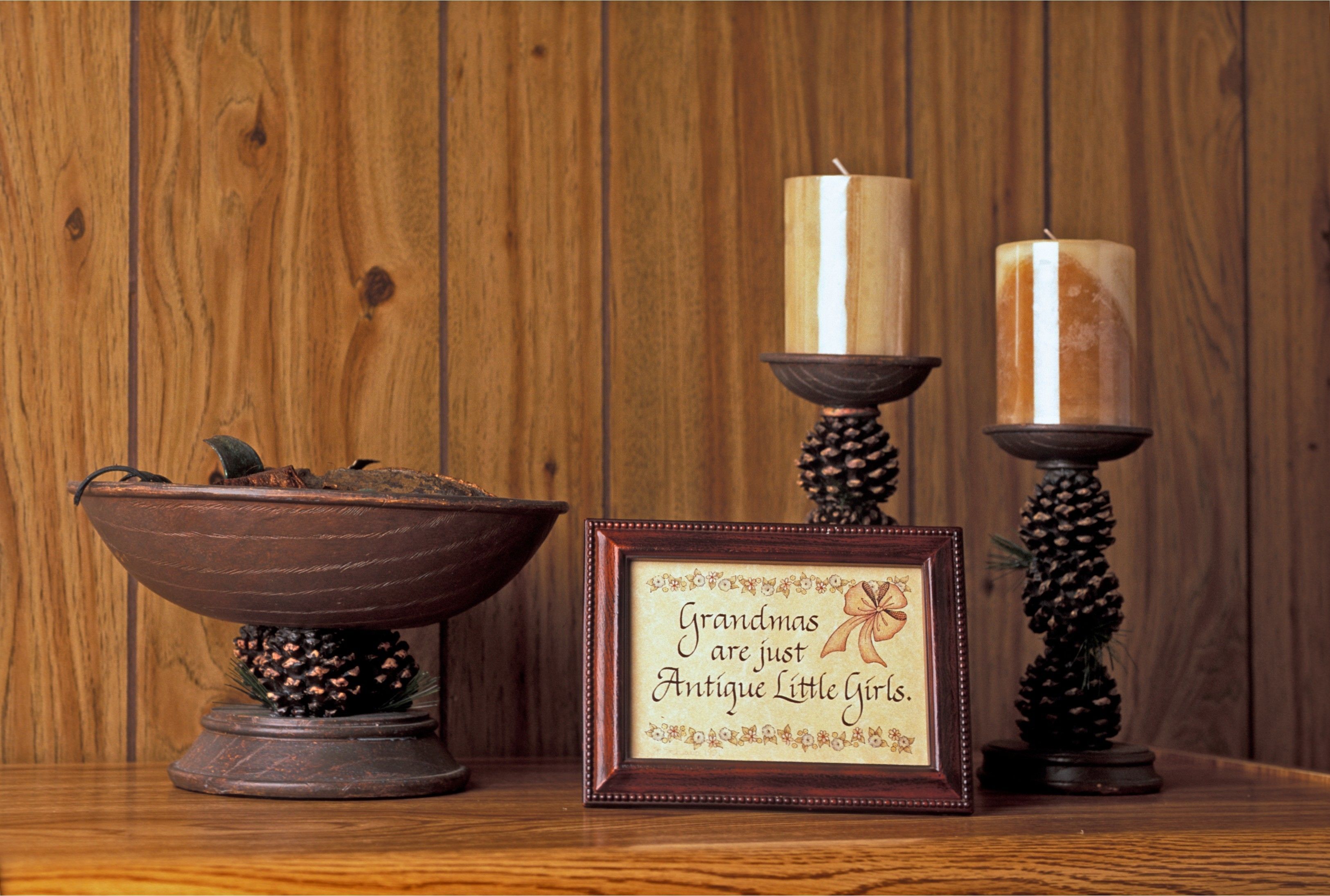 A wooden wall with a framed sign and two candles on stands.