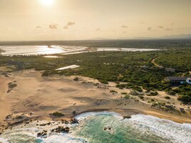 Vista aérea de una zona costera con playa, un pequeño poblado con casas y una gran masa de agua.