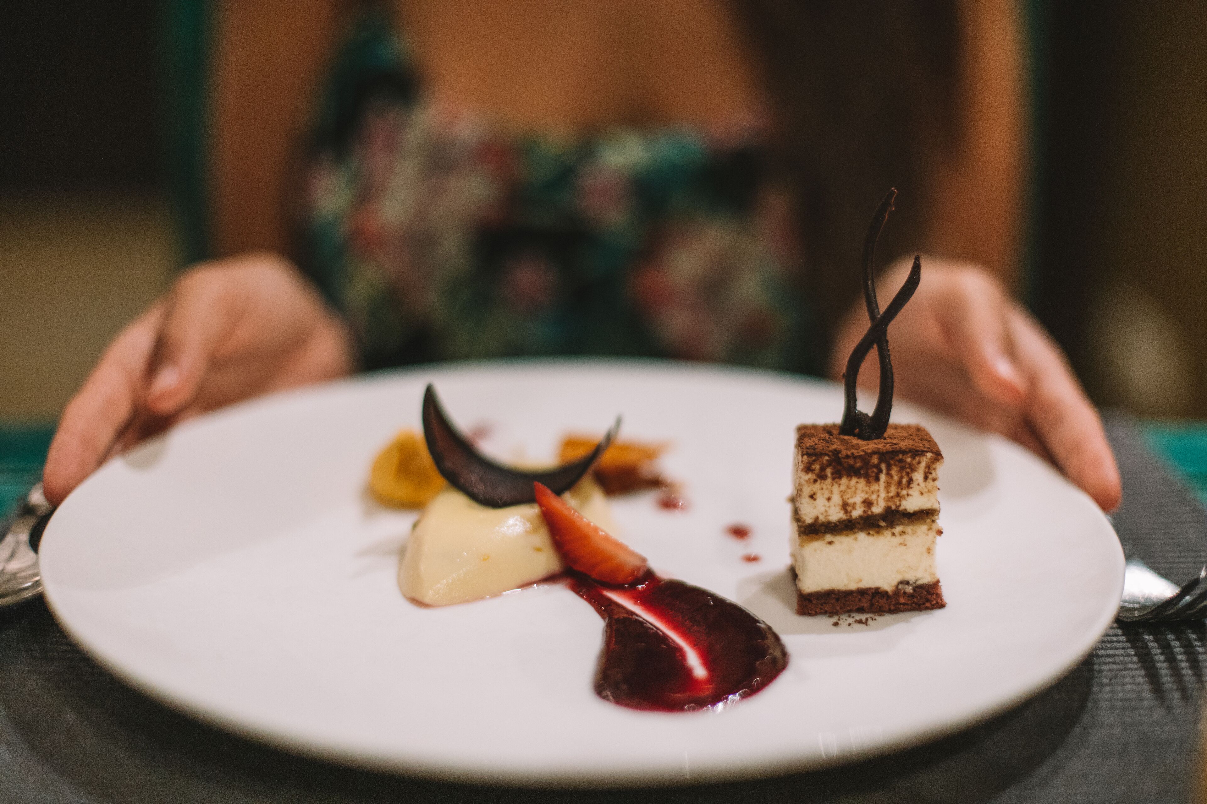 Un plato de postre con una porción de pastel, una bola de helado y salsa de frutos rojos.