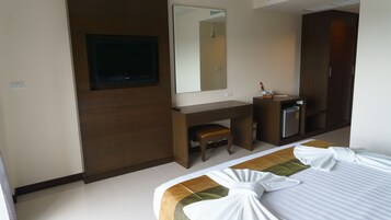 Una habitación de hotel con cama, escritorio, espejo y minibar.