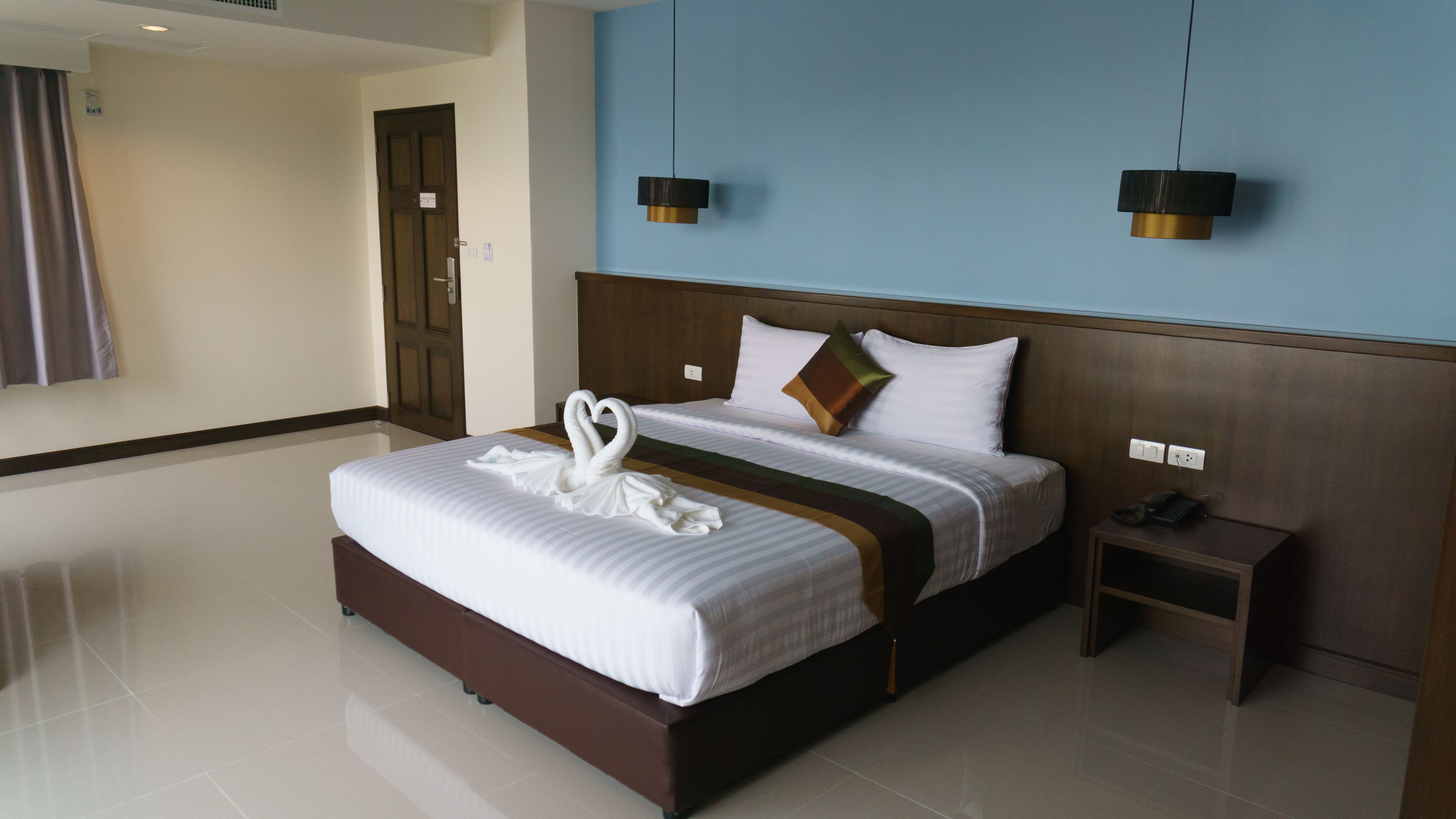 Camera d'albergo con un letto grande, una testata in legno, un comodino e due lampade a sospensione.
