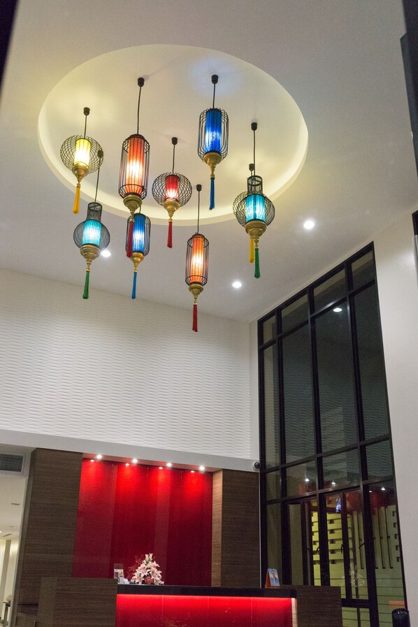 A hotel reception area with a red counter and multiple hanging decorative light fixtures. - Visa Hotel Hua Hin (Hua Hin)