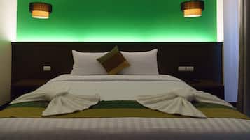 Una cama bien hecha con sábanas blancas, una manta a rayas verde y amarilla y una almohada marrón. Hay dos lámparas de pared a cada lado de la cama.