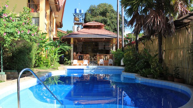 A swimming pool with a metal ladder, surrounded by a wooden fence and potted plants. - Darayonan Lodge (Coron)