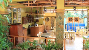A restaurant with a wooden interior, a counter, and several tables and chairs. - Darayonan Lodge (Coron)