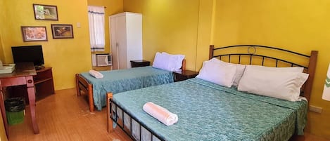 Una habitación con dos camas, televisión, armario y una pequeña mesa.
