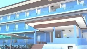 Um hotel de vários andares com fachada azul, varandas em cada pavimento e uma placa indicando que é um hotel.