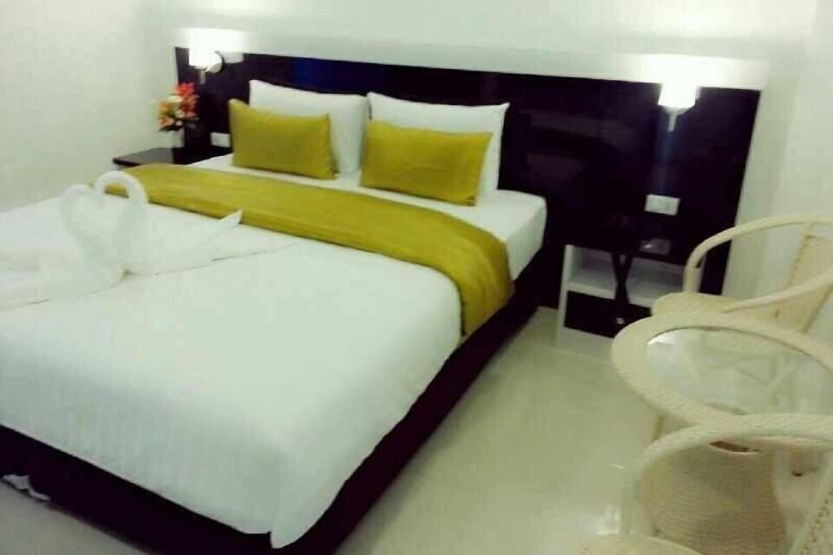 Una habitación de hotel con una cama bien hecha, una mesita de noche con lámpara y una silla.