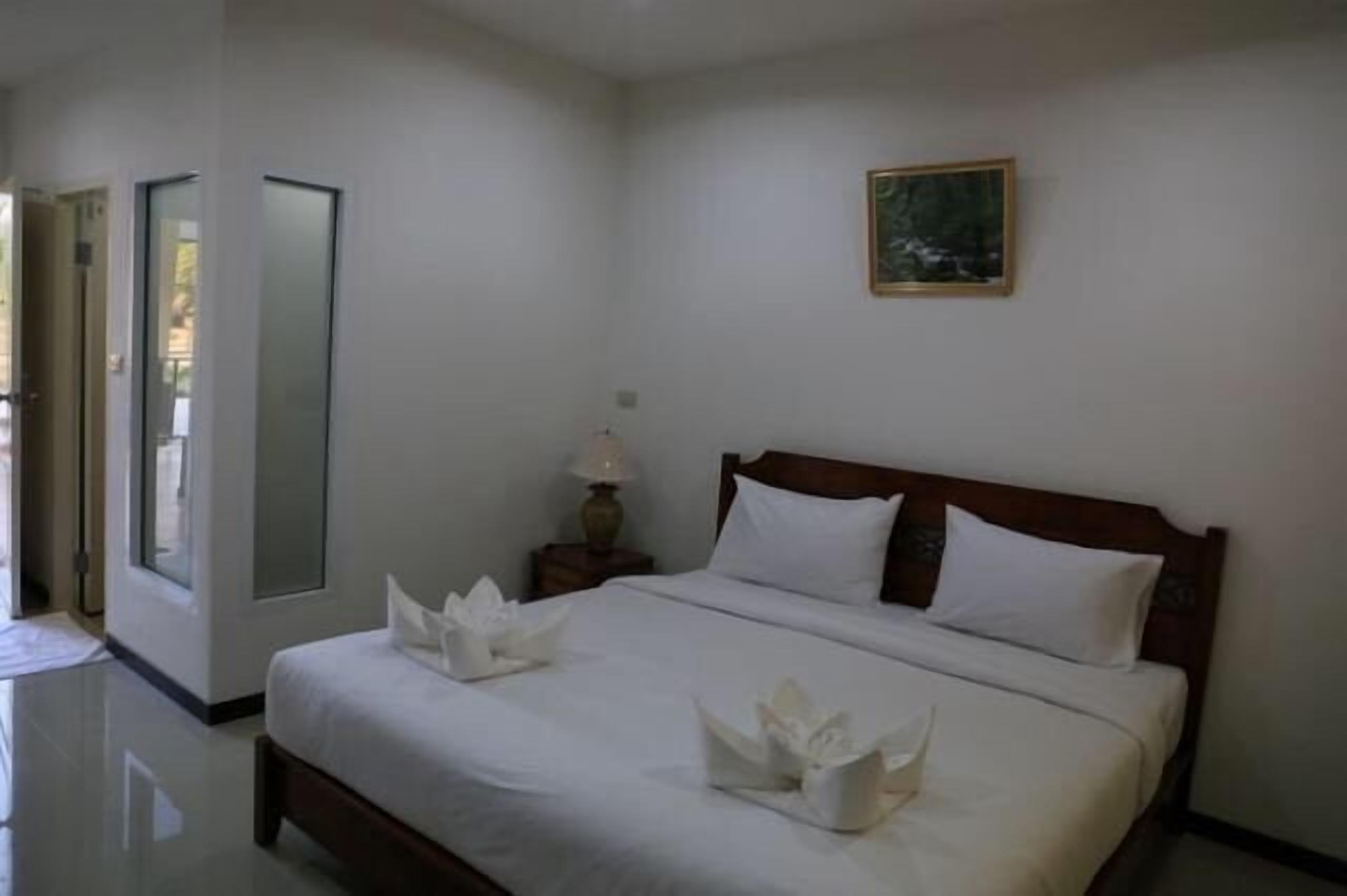 A hotel room with a large bed, a nightstand with a lamp, and a painting on the wall.