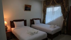 Quarto de hotel com duas camas, uma mesa de cabeceira com abajur e um quadro na parede.