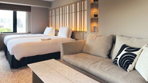 Une chambre d’hôtel avec deux lits, un canapé, une table basse et une étagère murale agrémentée d’objets décoratifs.