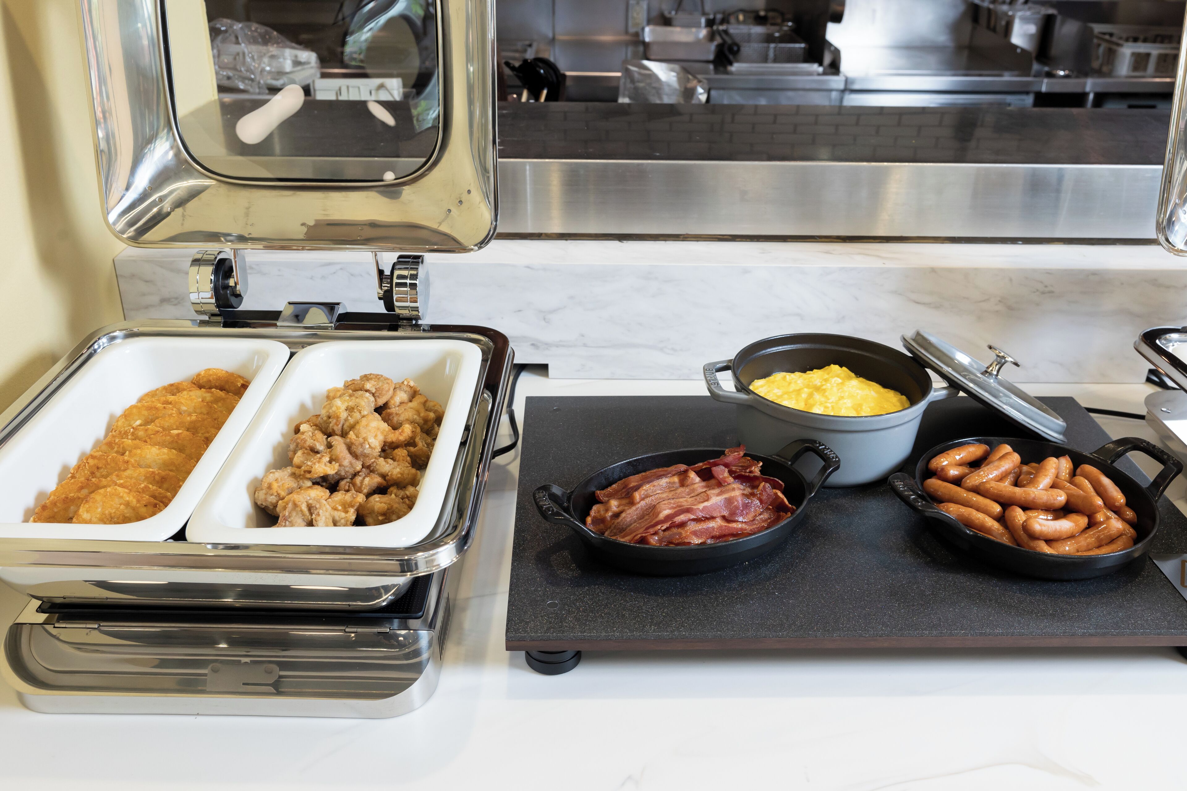 A buffet with various food items including fried chicken, sausages, and macaroni and cheese.