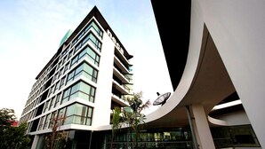 Een modern hotel met een hoge, hoekige gevel, meerdere balkons en grote ramen.