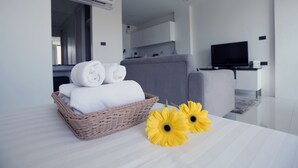 Een moderne woonkamer met een grijze bank, een televisie en een rieten mand met handdoeken.
