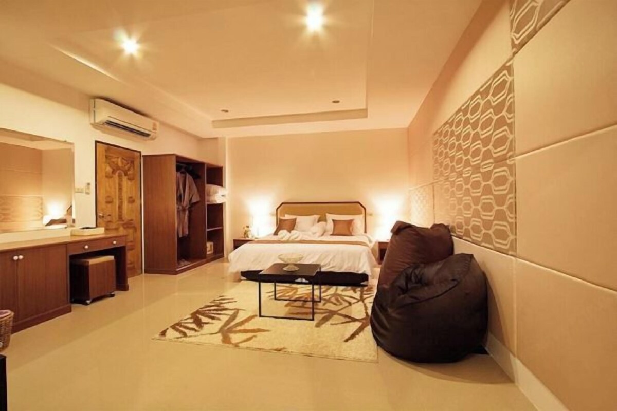 Una habitación de hotel moderna con cama, mesita de noche y un espejo grande.