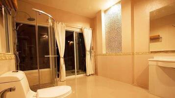 A bathroom with a glass shower enclosure, a toilet, and a sink.