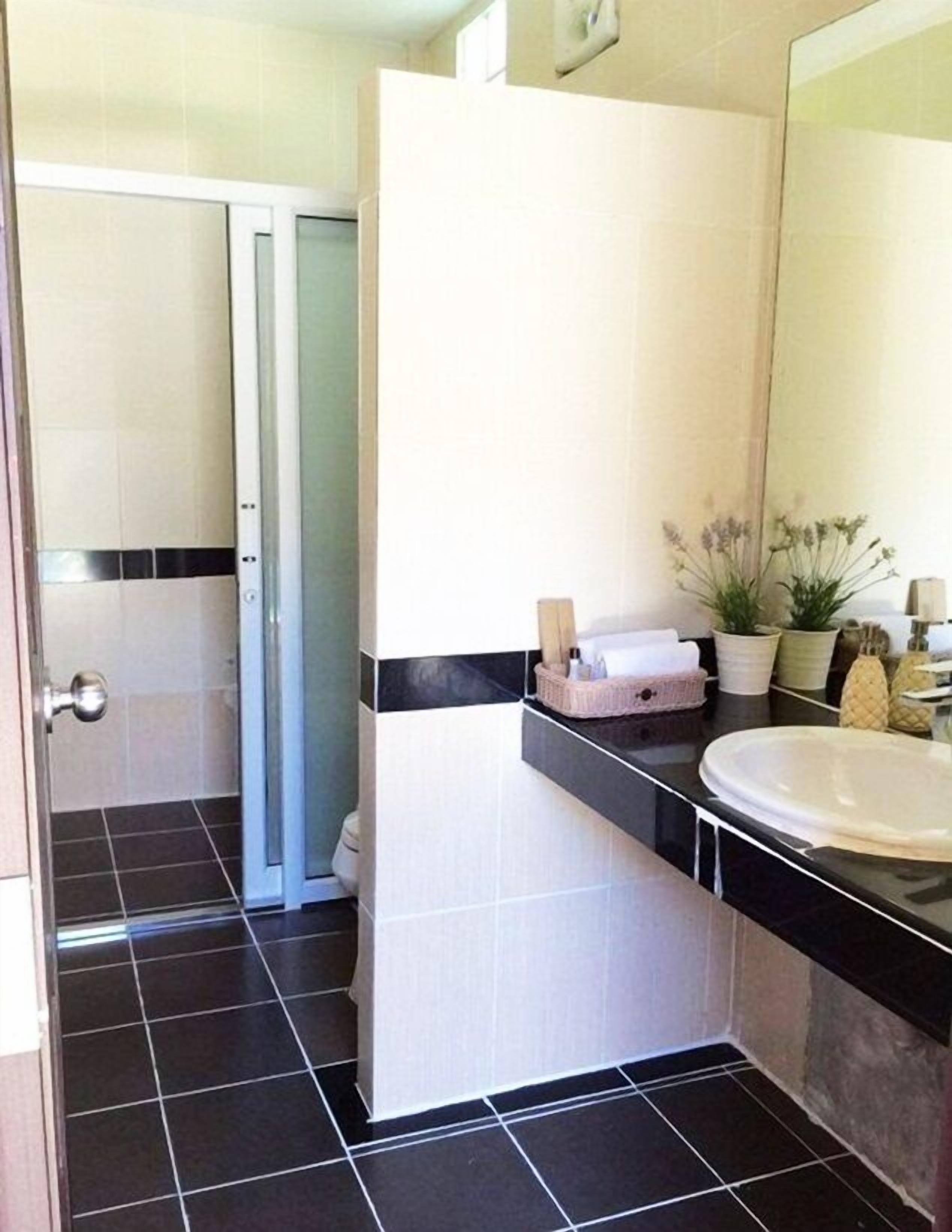 Un baño moderno con suelo de baldosas blanco y negro, un lavabo blanco y un espejo.