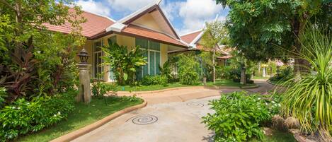 A traditional building with a curved roof, surrounded by lush greenery and a paved pathway.