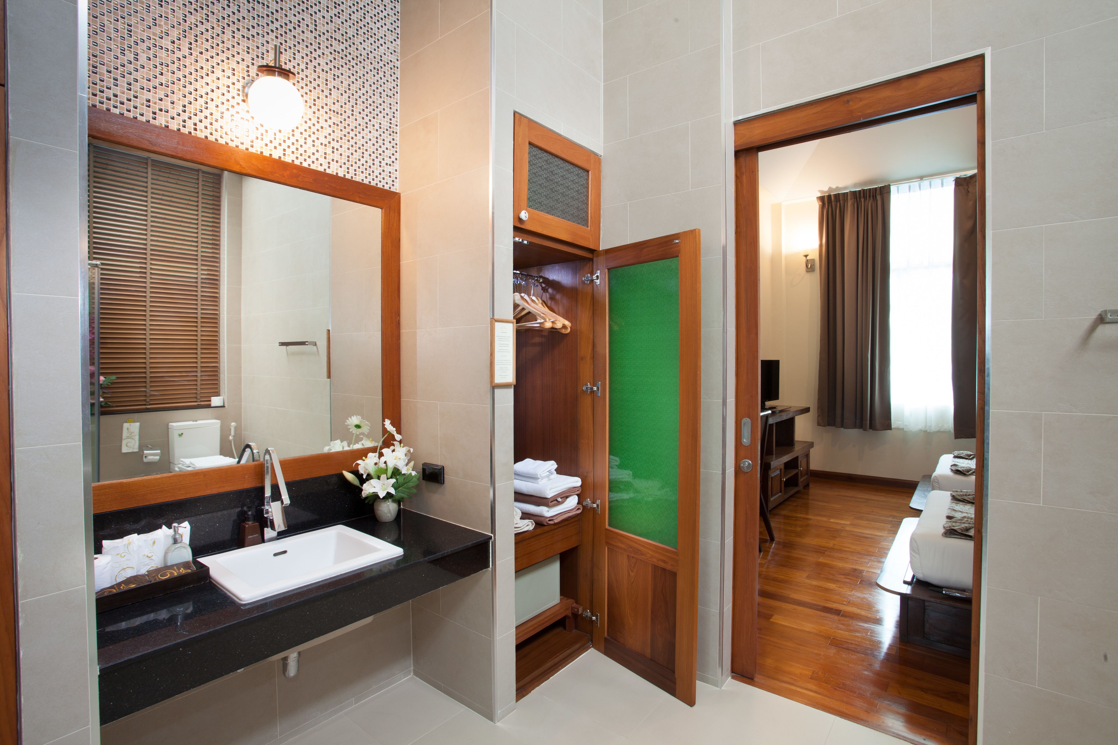 Un baño con lavabo, espejo y puerta de madera que da a un dormitorio.