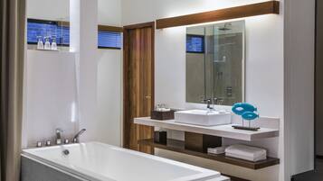 A modern bathroom with a large bathtub, two sinks, and a mirror.