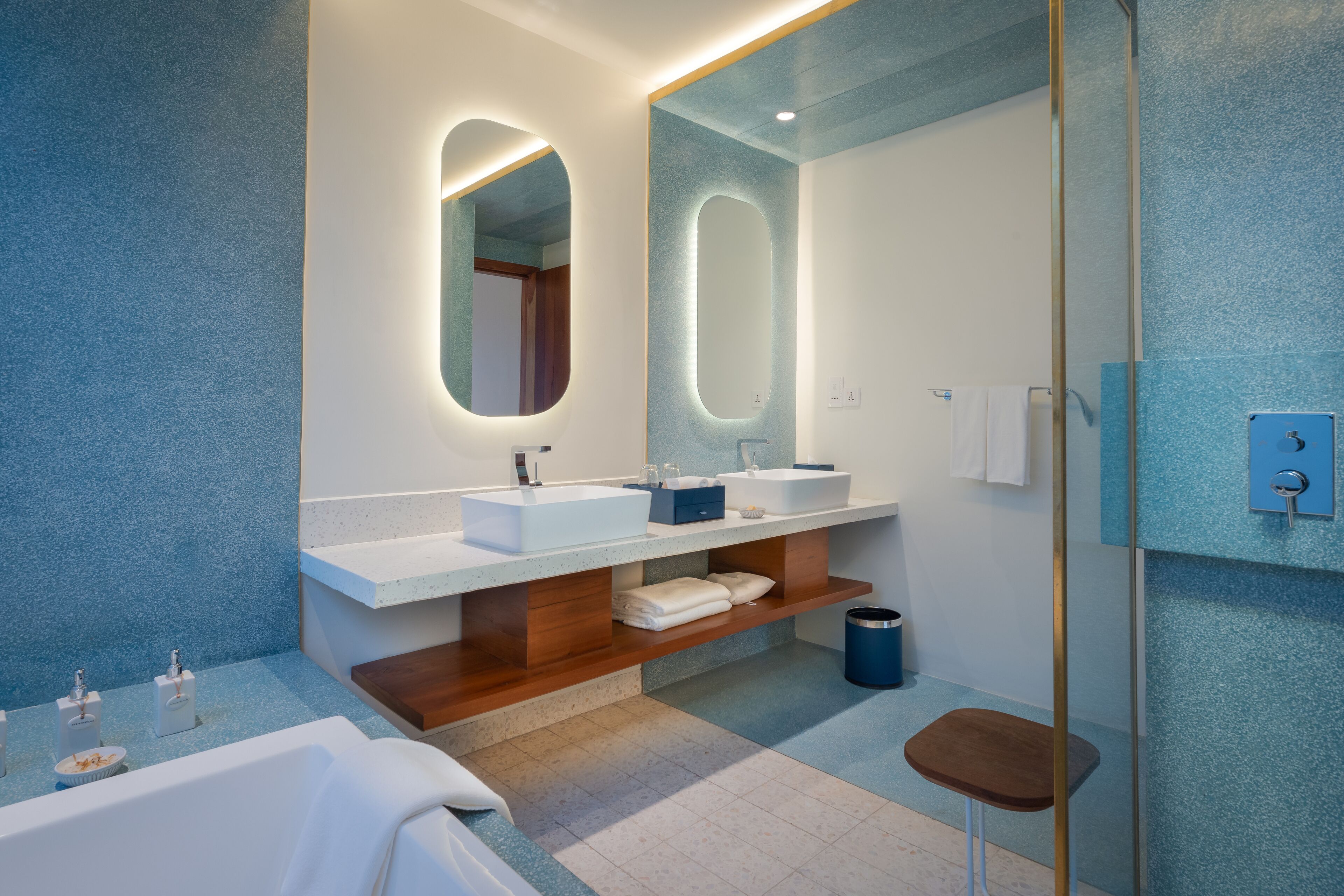 A modern bathroom with two sinks, a large mirror, and a wooden vanity.