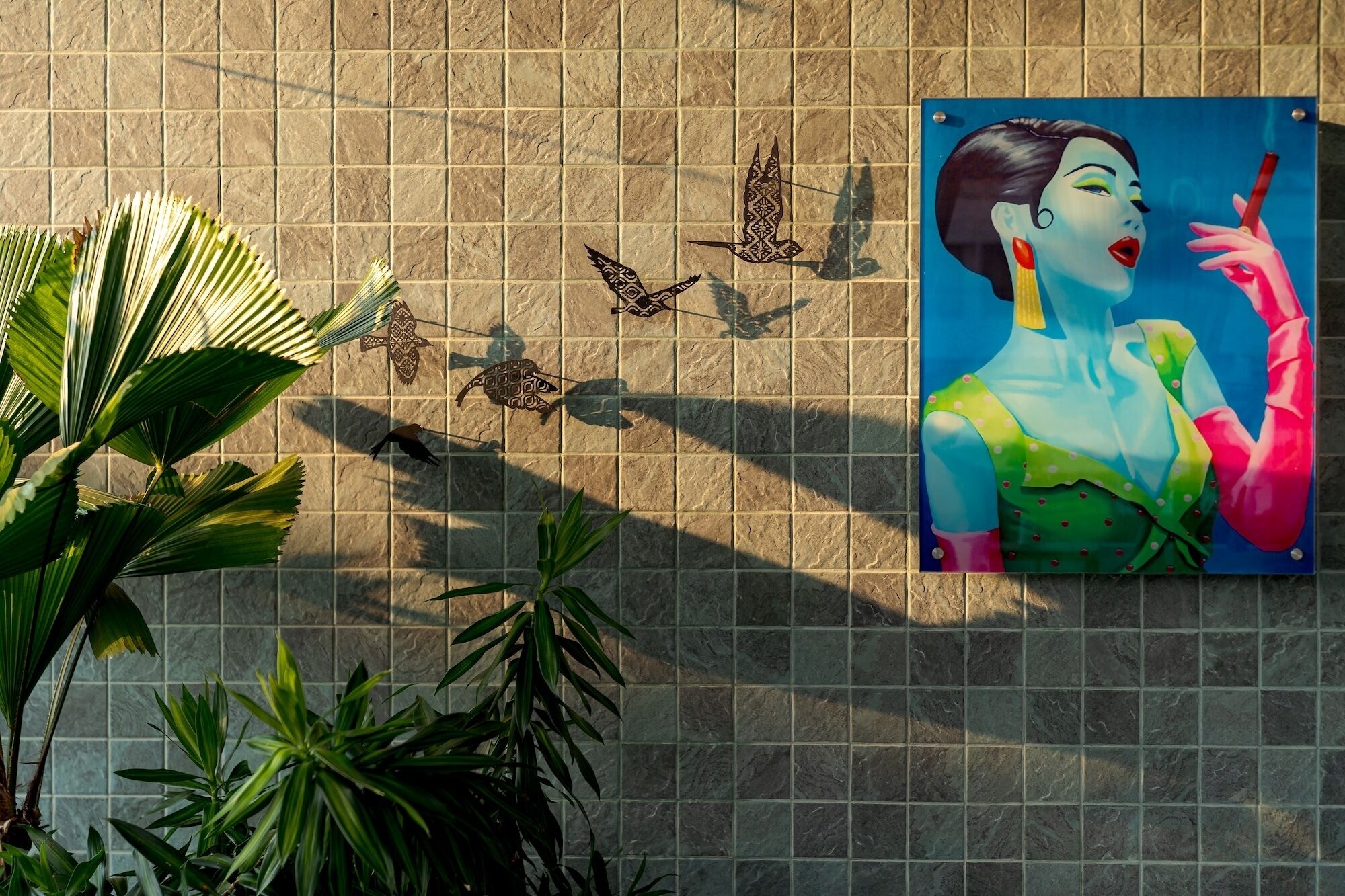 A tiled wall with a mural of a woman and birds.