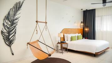 A modern hotel room with a large bed, a hanging chair, a nightstand, and a wall art piece.