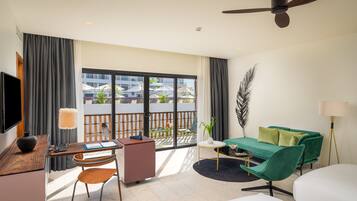 Quarto de hotel moderno com escrivaninha, cadeira, sofá verde e uma grande janela com vista para o exterior.
