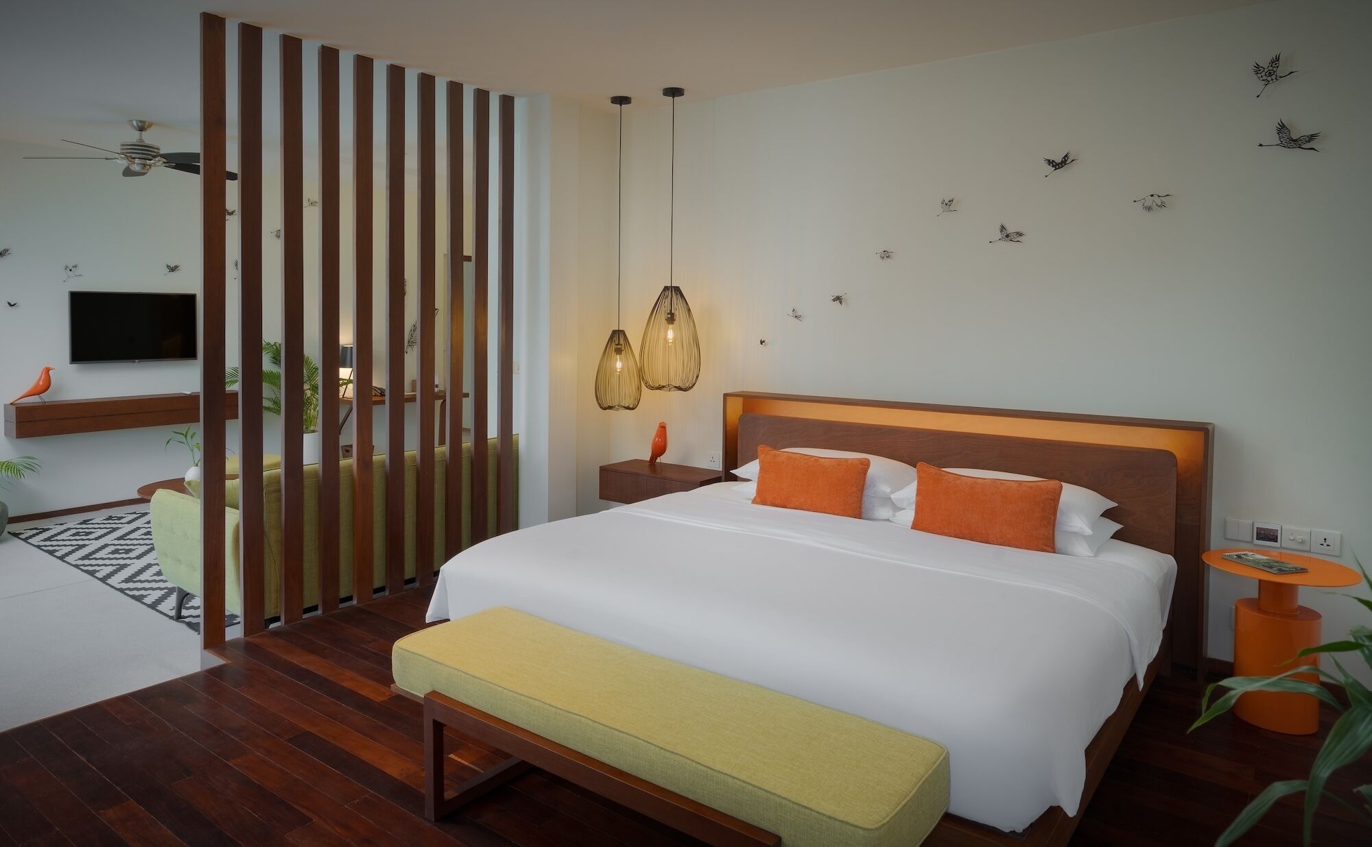 A modern bedroom with a wooden bed, a bench, a TV, and decorative wall art.