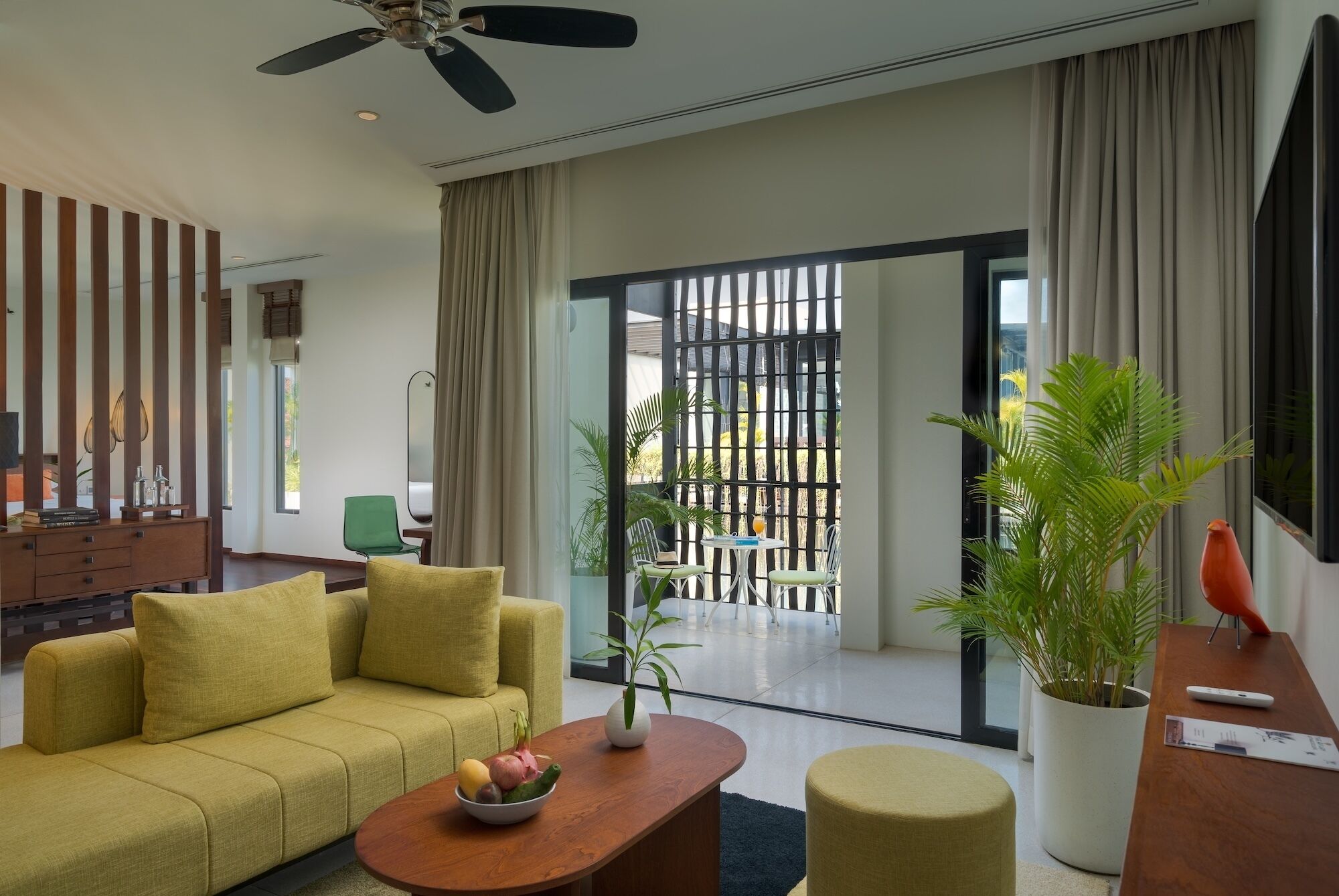 A modern living room with a sofa, coffee table, and a balcony with plants.