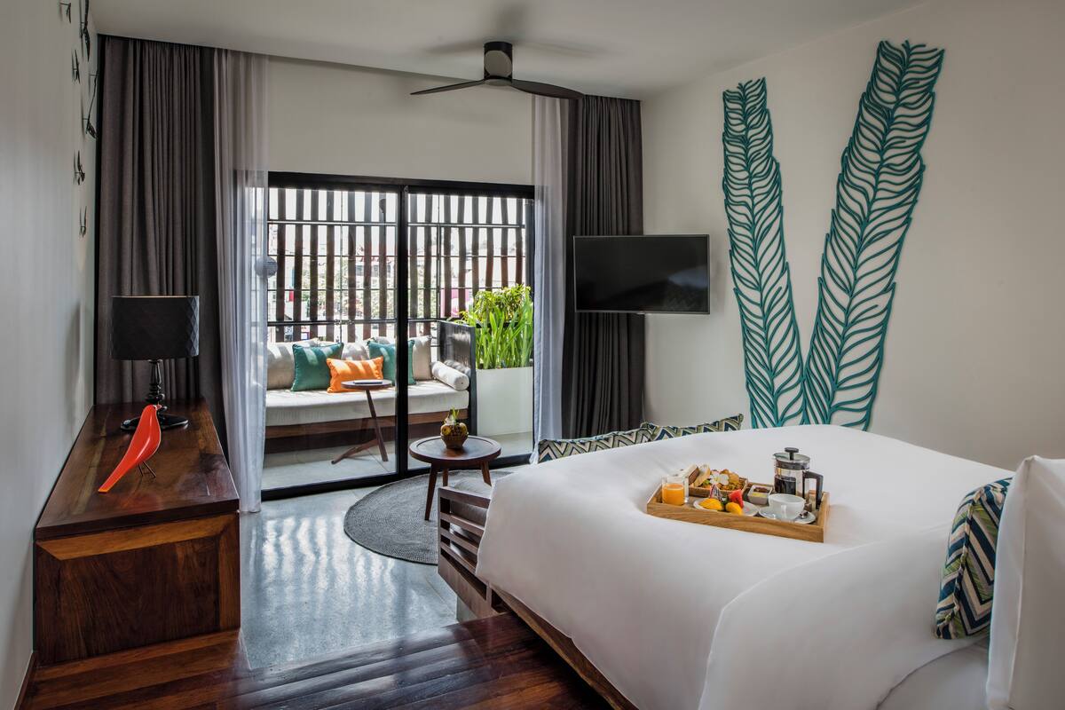 A hotel room with a bed, a desk, a TV, and a balcony with a view.