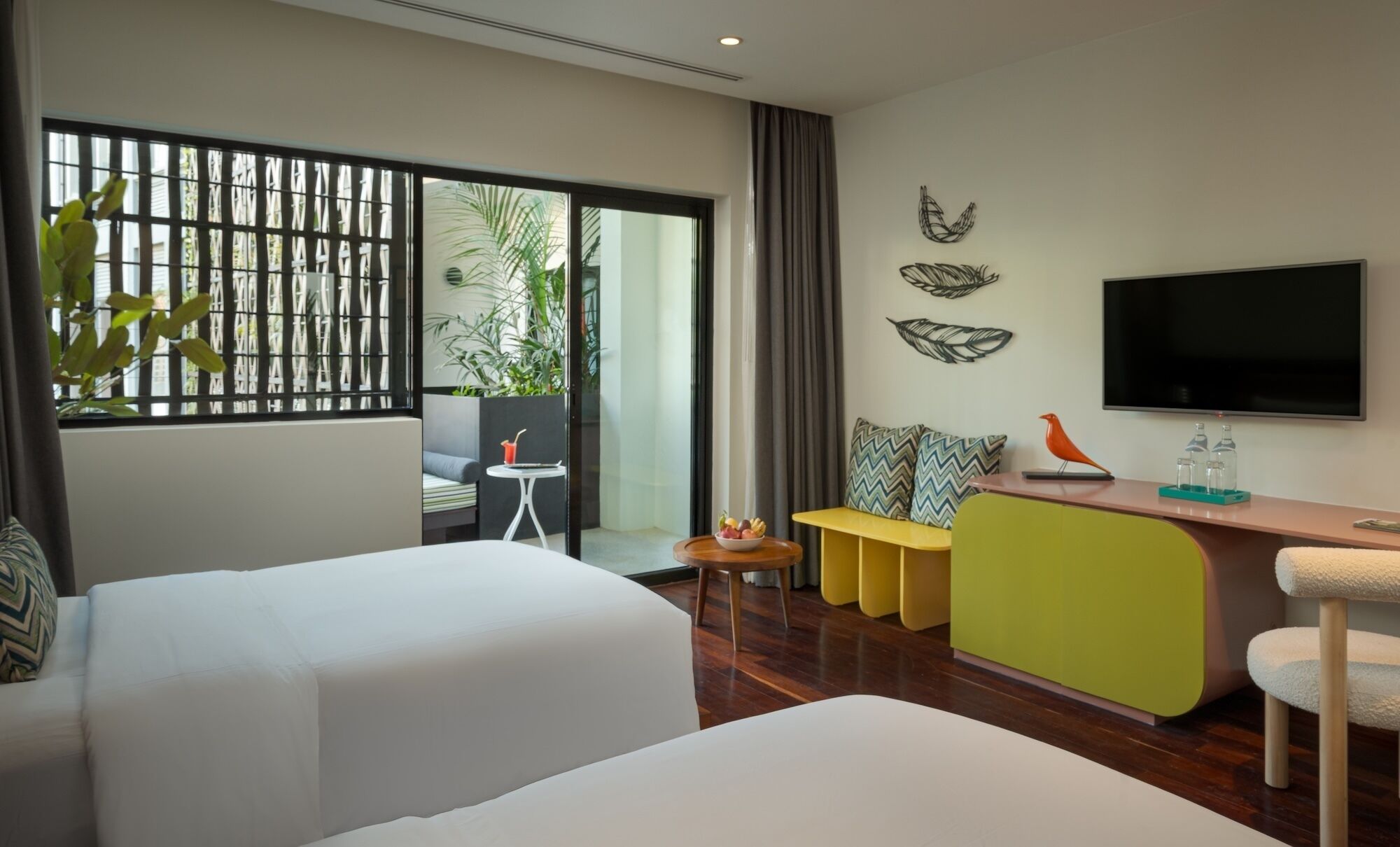 Una habitación de hotel moderna con una cama grande, un escritorio, un televisor y un balcón con plantas.