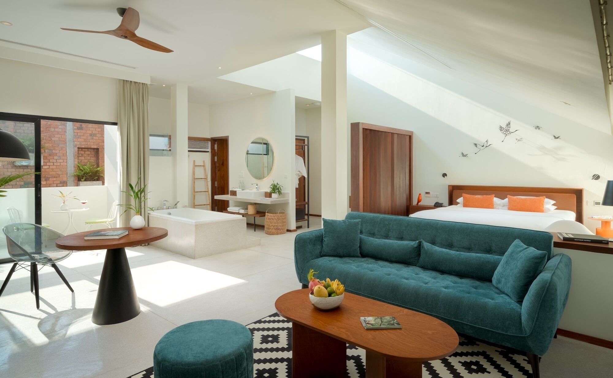 A modern hotel room with a large bed, a sofa, a dining area, and a balcony.
