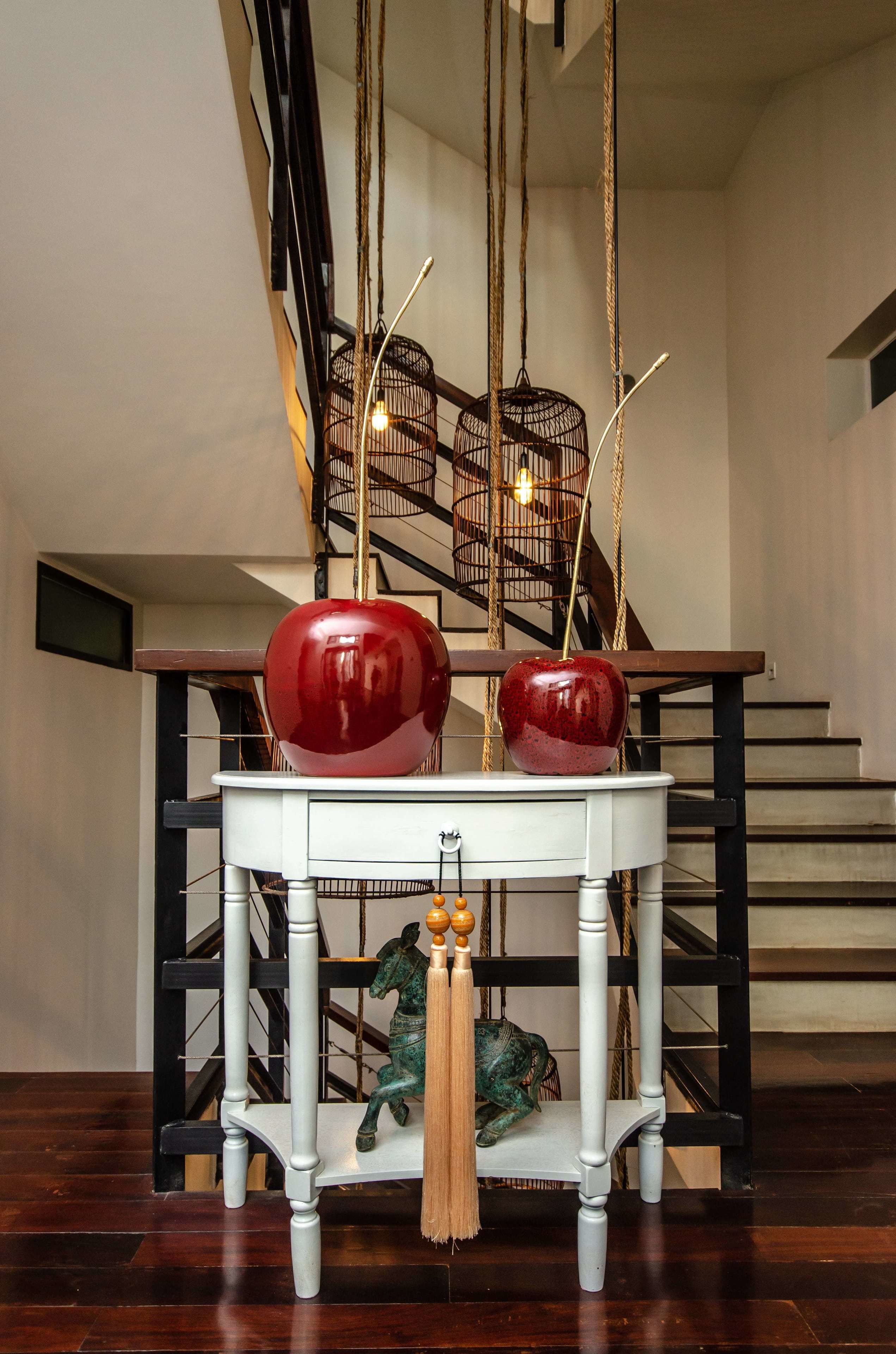 A staircase with a white table in the foreground, a green horse statue, and a red apple on the table.