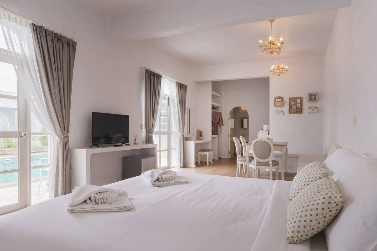 Ein Hotelzimmer mit Bett, Schreibtisch, Fernseher und Blick ins Freie.