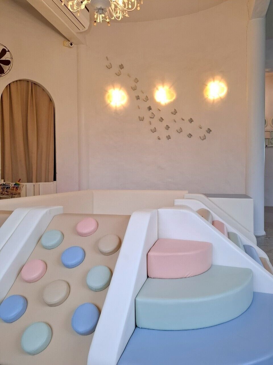 A children's play area with a soft play structure, a wall-mounted light fixture, and a radiator.