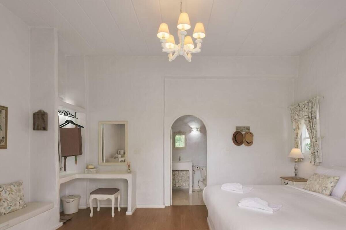 Ein Hotelzimmer mit Bett, Schreibtisch, Stuhl, Spiegel und einer Kristallleuchtre.