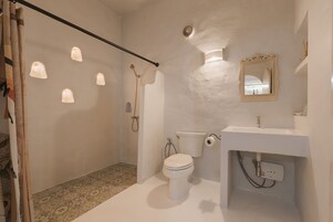 A bathroom with a toilet, sink, shower, and decorative lights.