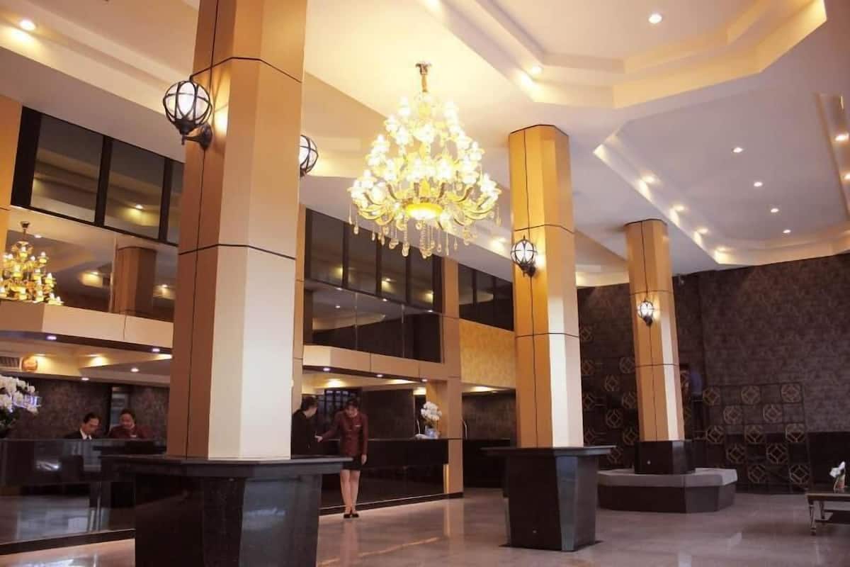 Um hall de entrada com um lustre imponente, vários balcões de recepção e pé-direito alto.