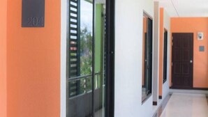 A hallway with a door labeled '204' and a window with blinds. - BH Place Apartment (Kanchanaburi)
