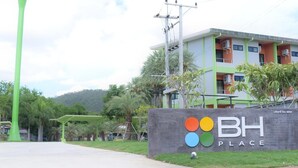 A building with a sign reading "BH PLACE" and a colorful logo. - BH Place Apartment (Kanchanaburi)