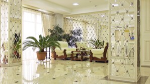 A spacious lobby with a polished floor, comfortable seating, and decorative plants. - Discovery Hotel (Bishkek)