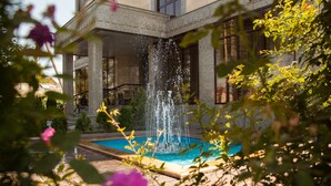 A courtyard with a fountain, a pool, and a building with columns. - Discovery Hotel (Bishkek)