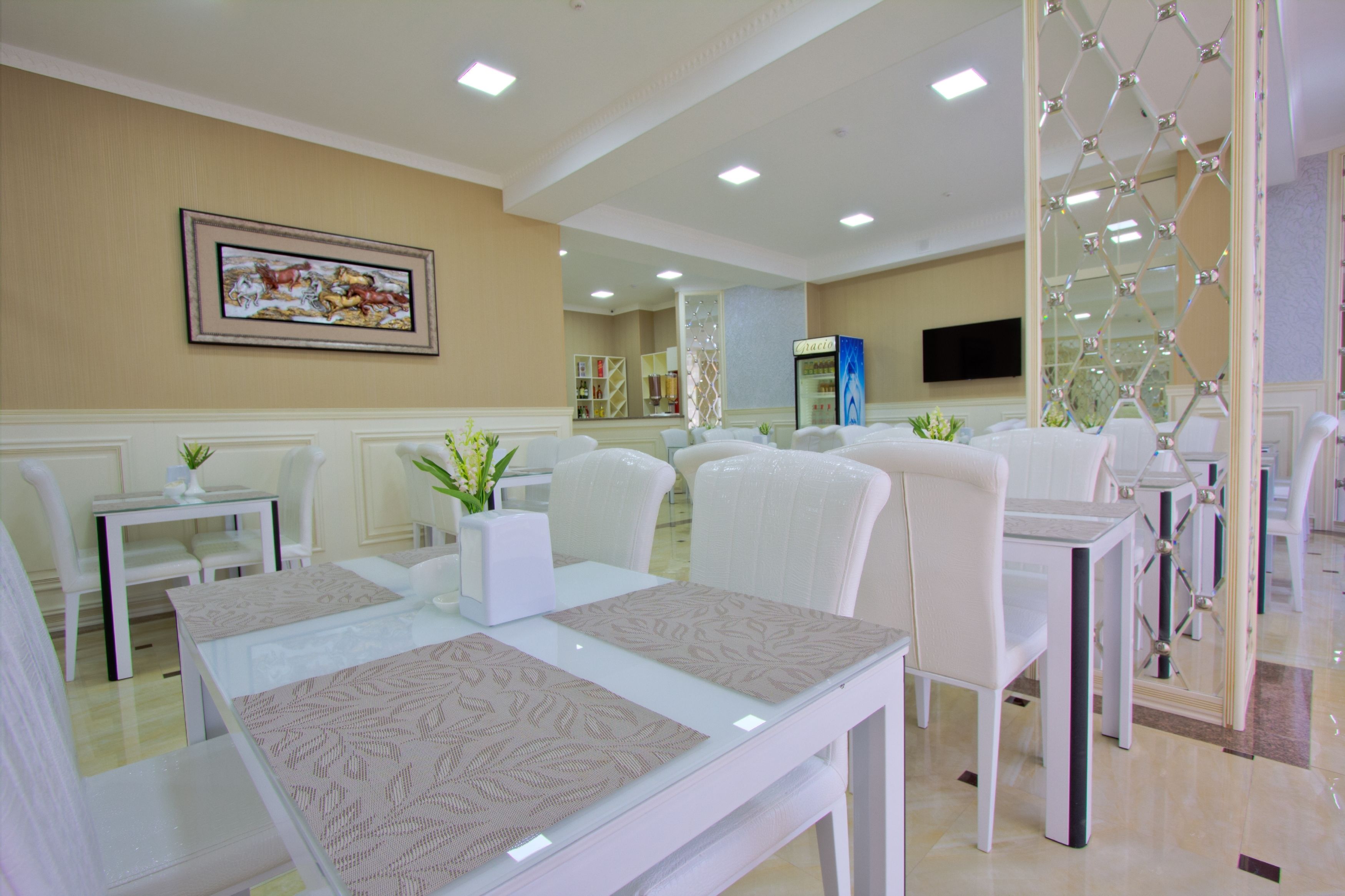 A modern hotel lobby with a reception desk, seating area, and a large framed artwork on the wall.