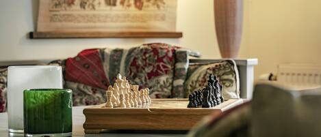 A chessboard on a table with a green glass and a white candle.