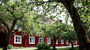 A red building with white windows, surrounded by green grass and trees. - Gripsholms Bed & Breakfast (Mariefred)