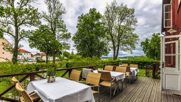 An outdoor dining area with tables and chairs, surrounded by greenery and trees. - Gripsholms Bed & Breakfast (Mariefred)