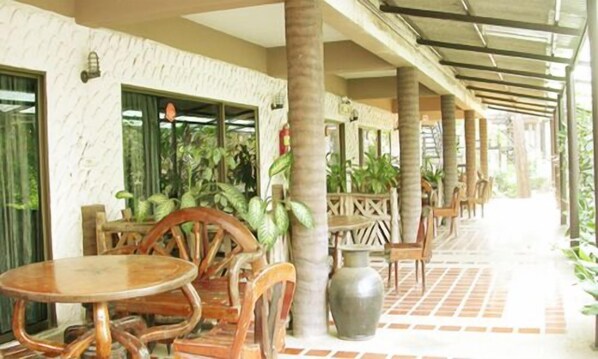 A covered outdoor seating area with wooden furniture and potted plants.